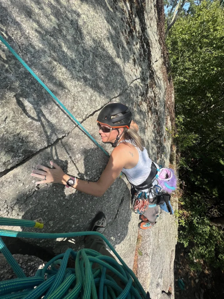 A rock climber ascending a challenging route at Devils Tower, showcasing safety gear and climbing techniques